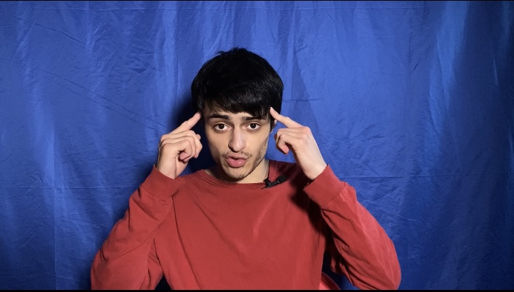 Matthew Luna sitting on a chair pointing to his head while explaining habit mindset.